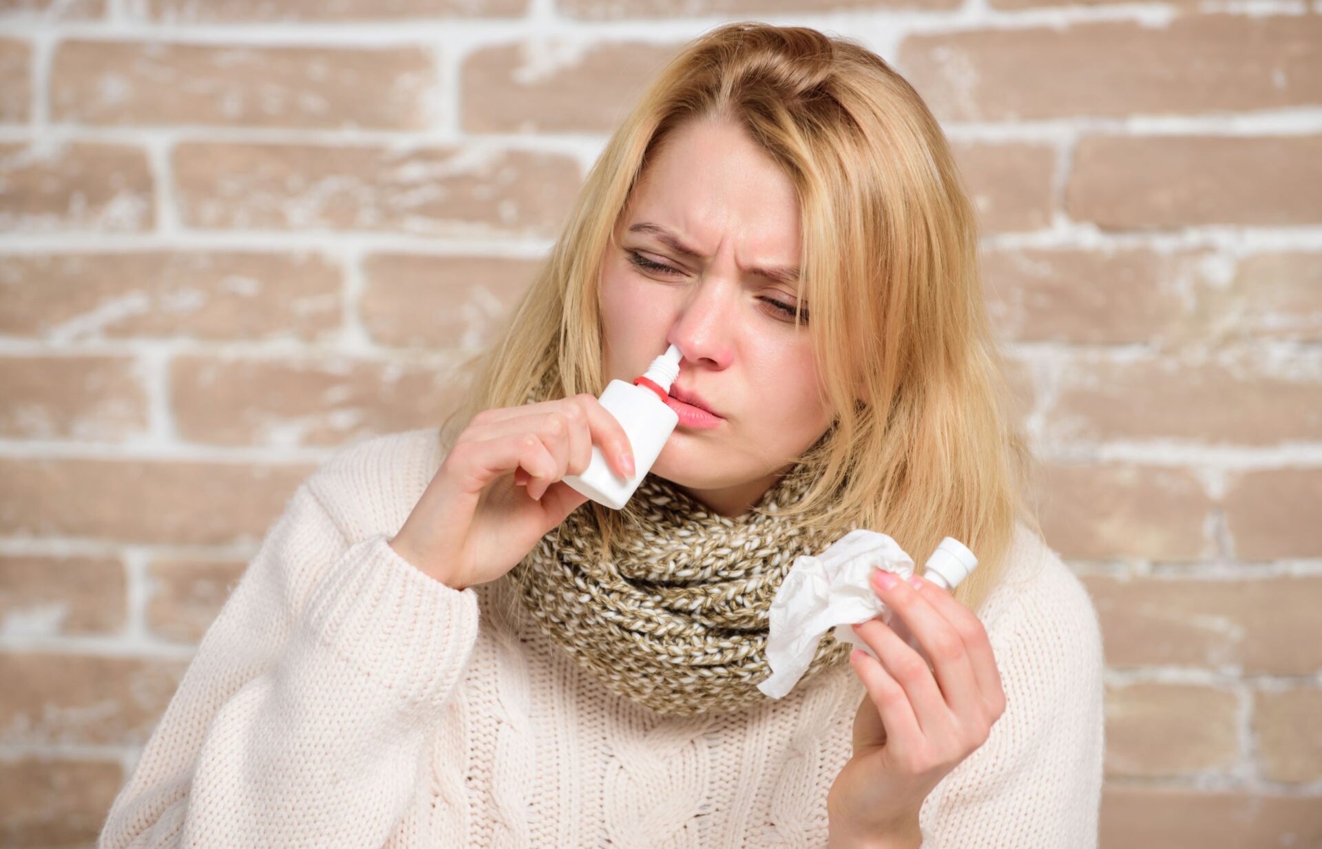 Alergiczny nieżyt nosa, kobieta aplikuje sobie krople do nosa