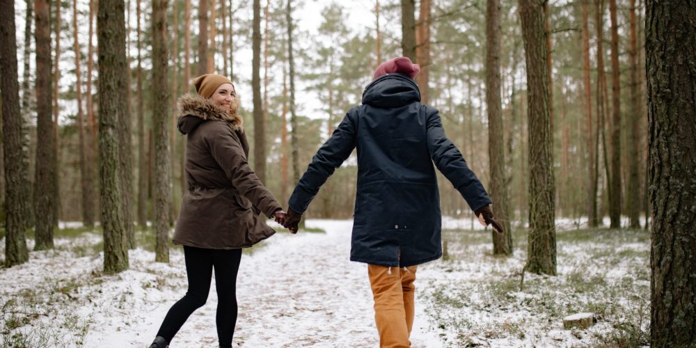 Two people in the forest, holding hands, winter, snow