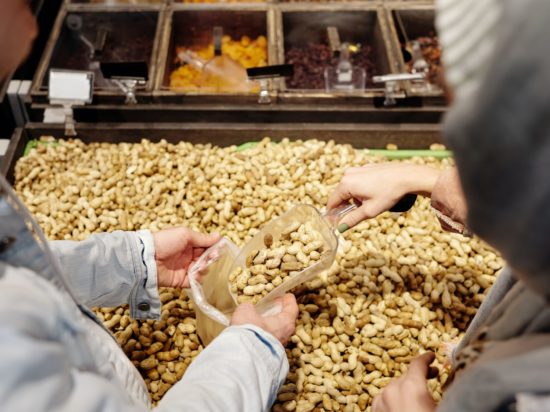 two people scoop peanuts in the shell into the purse