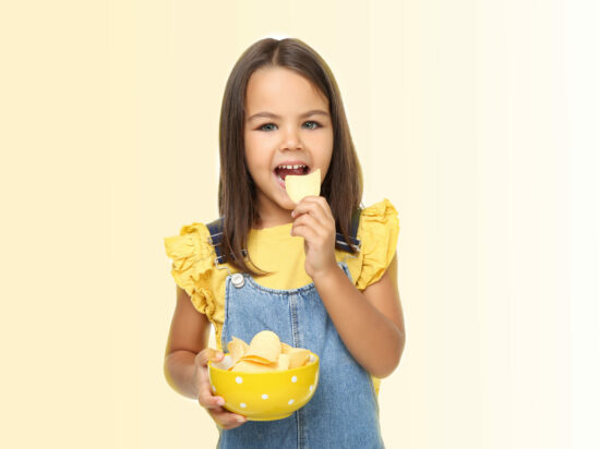 Little girl with potato chips in bowl on white background