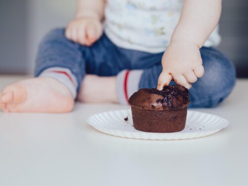 A little child puts a finger into a chocolate cupcake, czekolada i alergia