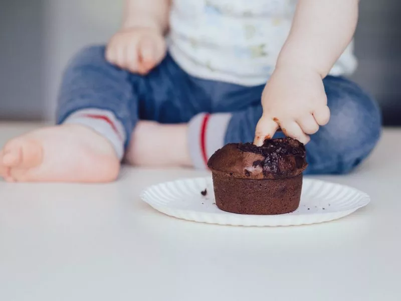 A little child puts a finger into a chocolate cupcake