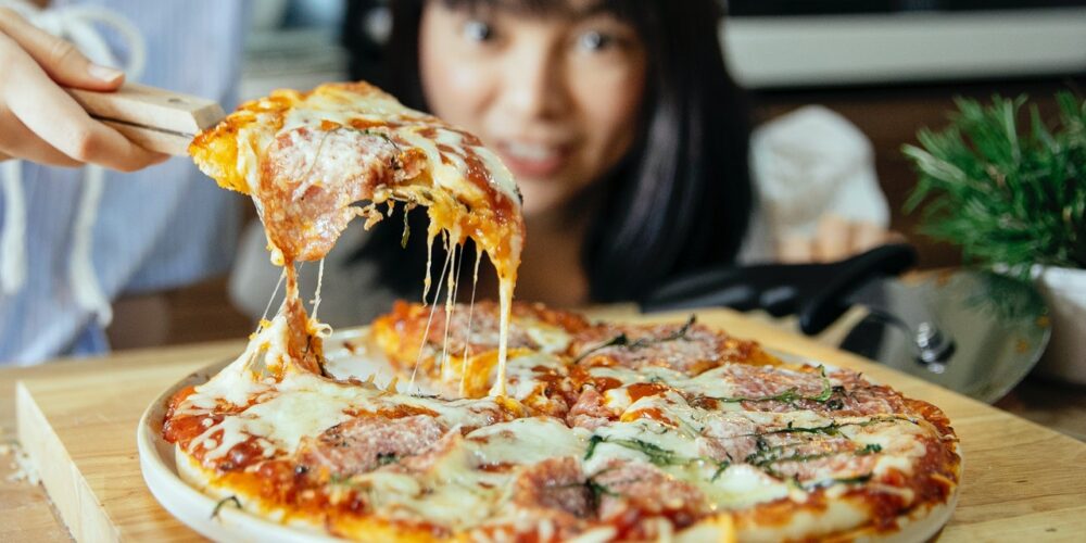 Pizza z ciągnącym serem, w tle kobieta, alfa‑laktoalbumina