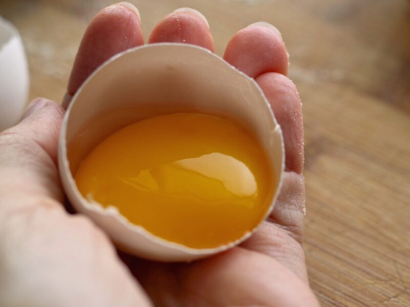 żółtko w połowie skorupki w dłoni, alergia na jajko