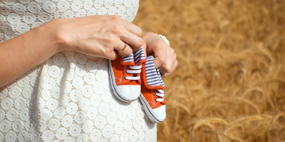 kobieta w ciąży, trzyma buciki dziecka, środki na alergię
