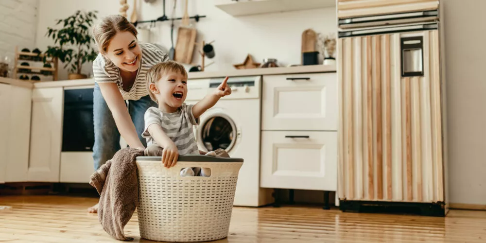 Happy family mother housewife and child son in laundry with washing machine