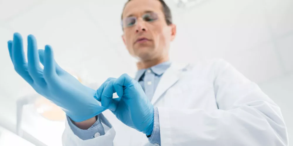 lekarz zakłada niebieskie rękawiczki lateksowe, alergia na lateksna