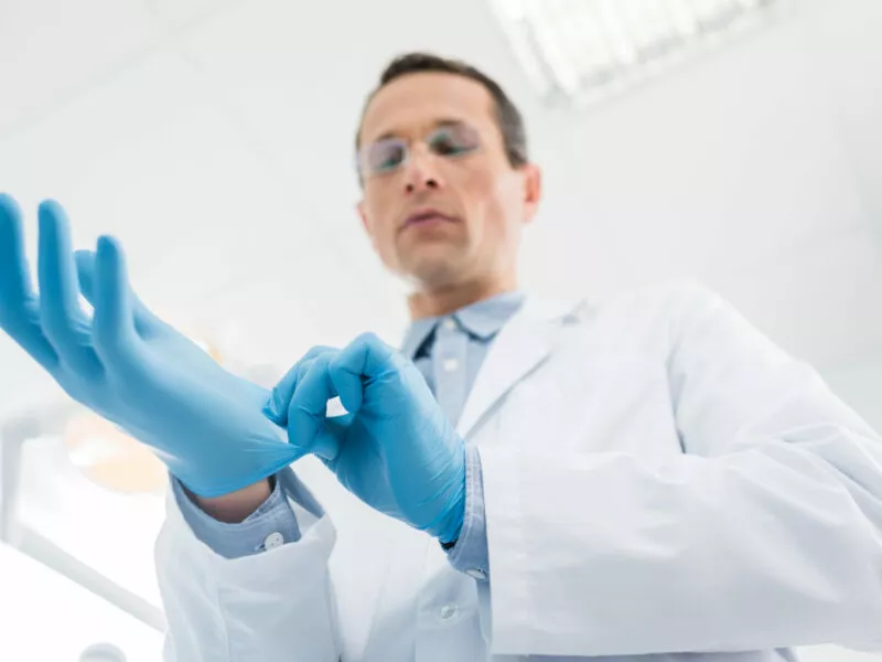 lekarz zakłada niebieskie rękawiczki lateksowe, alergia na lateksna