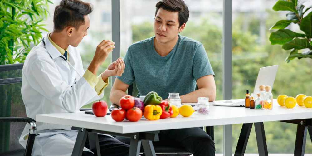 próba prowokacyjna, lekarz i pacjent siedzą przy stole, na stole owoce i warzywa