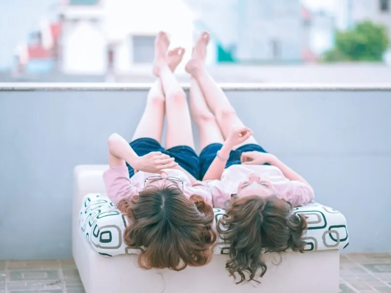 dwie dziewczynki, leżą na pufie na plecach