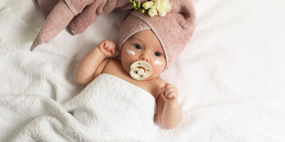 skóra atopowa, małe dziecko z kremem na twarzy po kąpieli