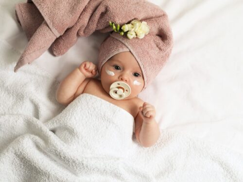 skóra atopowa, małe dziecko z kremem na twarzy po kąpieli