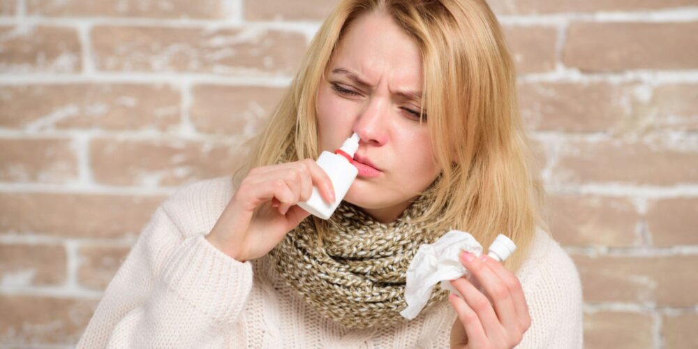 Alergiczny nieżyt nosa, kobieta aplikuje sobie krople do nosa