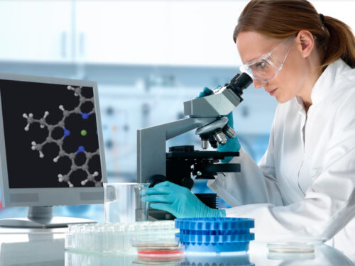 Kobieta w laboratorium patrzy przez mikroskop, diagnostyka molekularna