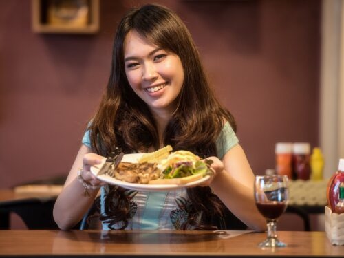 kobieta trzyma w rękach posiłek na białym talerzu, alergia mięso, alergia na mięso