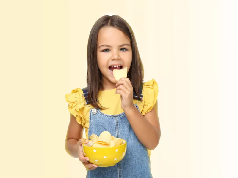 Little girl with potato chips in bowl on white background